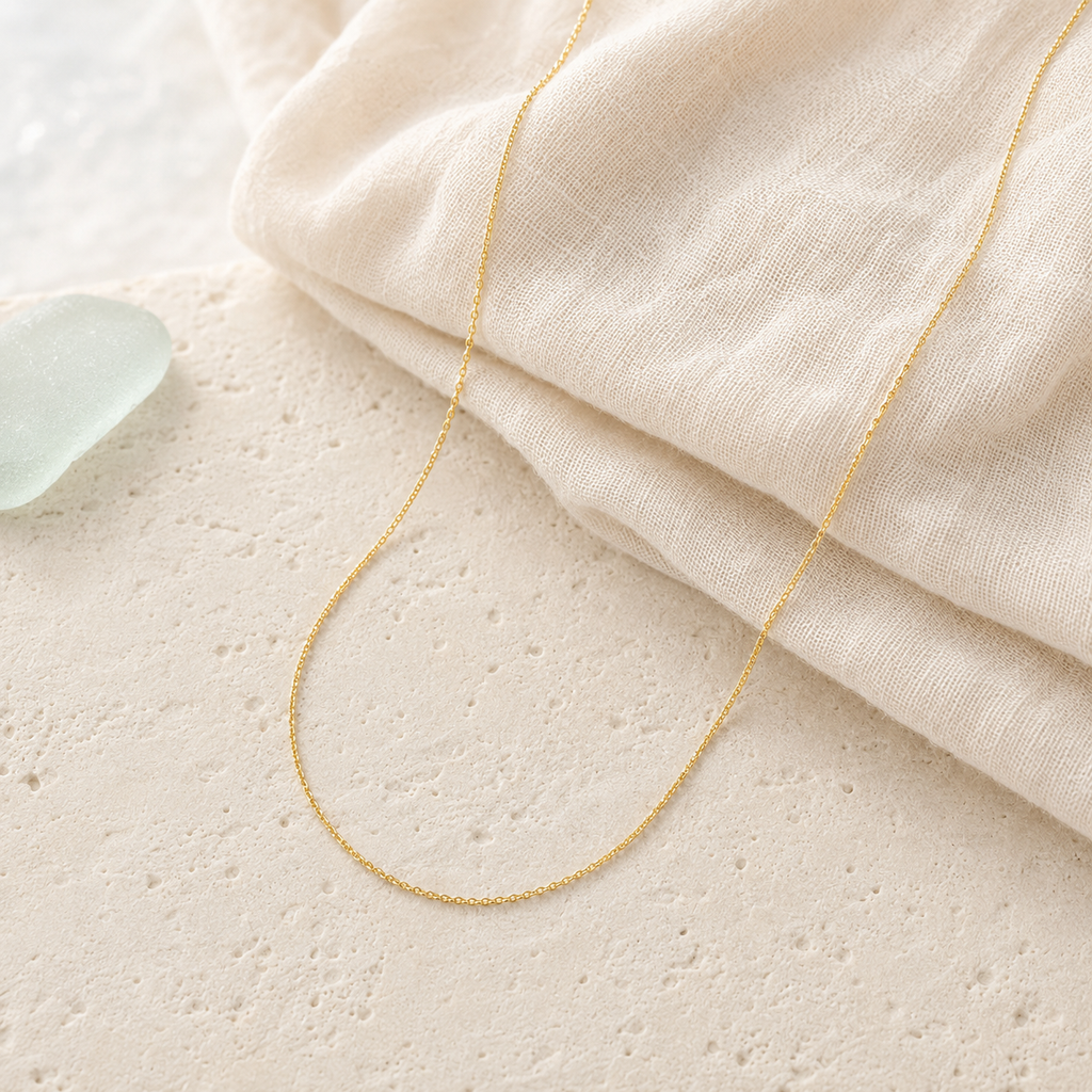 Solid gold dainty rope chain styled on ivory linen