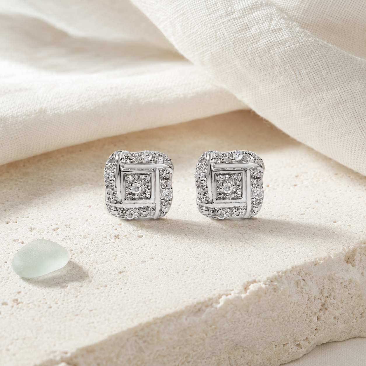 Sterling silver diamond knot earrings styled on pale stone