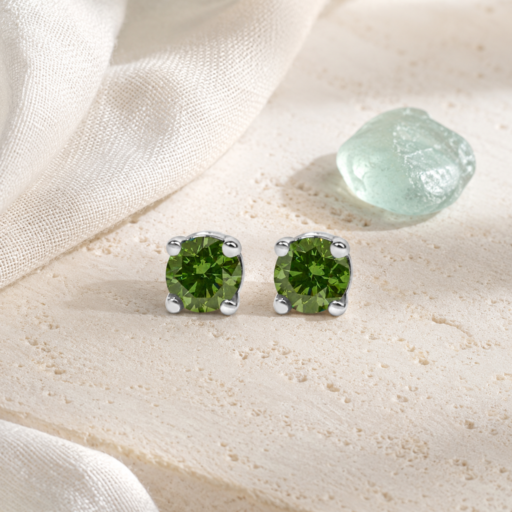 Green diamond stud earrings styled on pale limestone