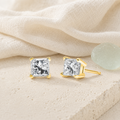 Princess-cut diamond stud earrings styled on ivory linen and limestone