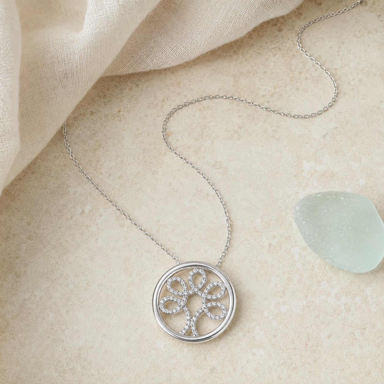 Sterling silver diamond Tree of Life necklace styled on pale stone